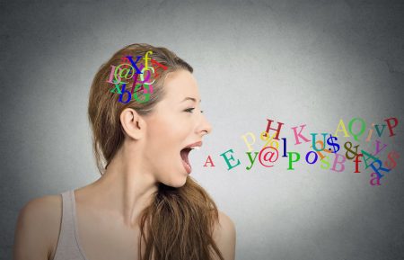 Side view portrait woman talking with alphabet letters in her head and coming out of her open mouth isolated grey wall background. Human face expressions, emotions. Communication, intelligence concept